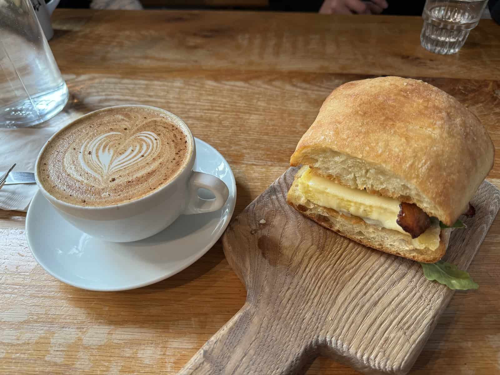 A sandwich and a cup of coffee on a wooden board at Fox in the Snow Cafe