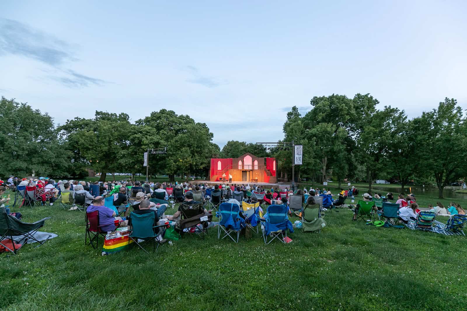 Audience seated in the park for a summer theatre performance at Schiller Park