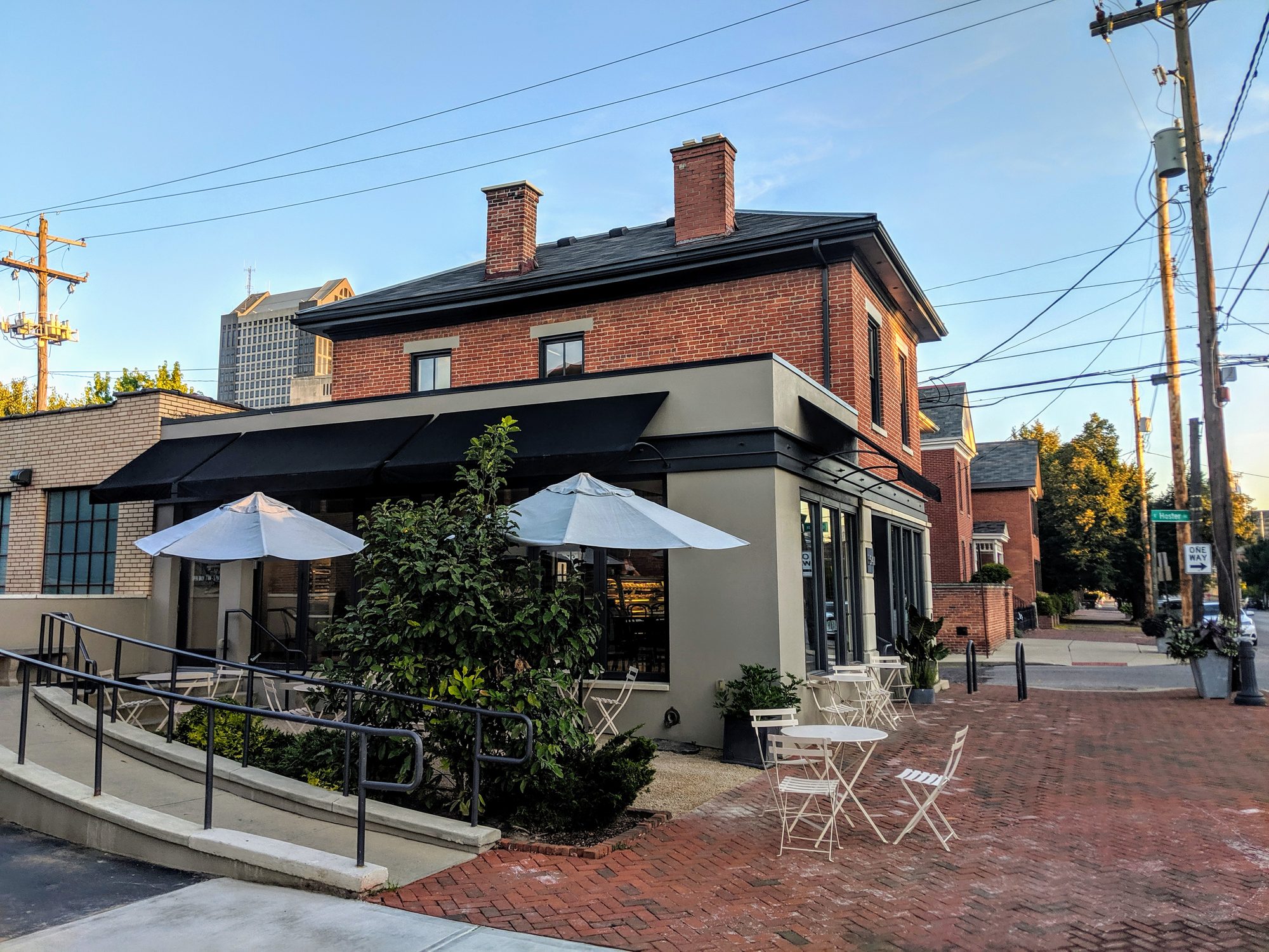 Pistacia Vera patisserie corner building with patio seating and downtown Columbus skyline behind